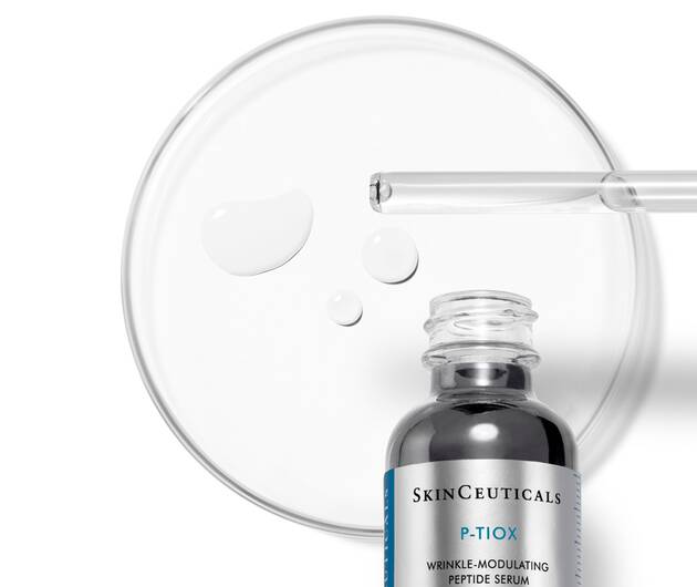 Ein Hautpflege-Serum von SkinCeuticals steht neben einer Petrischale mit Tropfen. Ideal fur die Faltenbehandlung.