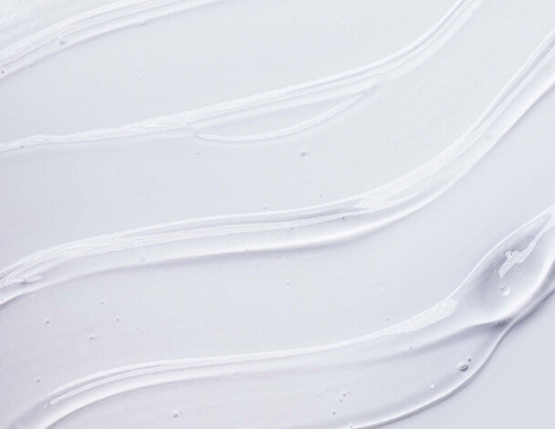 close-up of smooth, white cream or gel texture with flowing lines on a light background