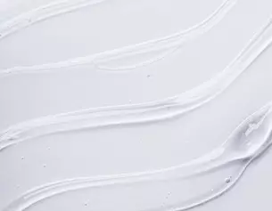 close-up of smooth, white cream or gel texture with flowing lines on a light background