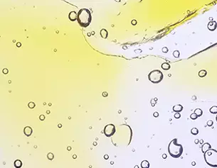 Bubbles d'air flottant dans un liquide transparent aux teintes jaune et claire, creant un effet visuel delicat.