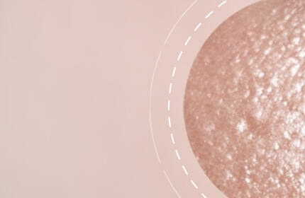 Close-up of a textured skin surface with subtle variations in color and sheen, set against a smooth, larger background.