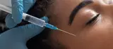 Frau erhalt eine Gesichtsbehandlung, wahrend ein Pinsel eine Losung auf die Haut auftragt.