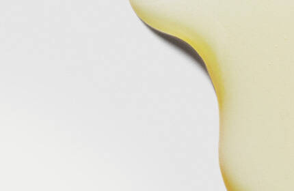 Abstract image featuring smooth, yellow oil droplets against a light background.