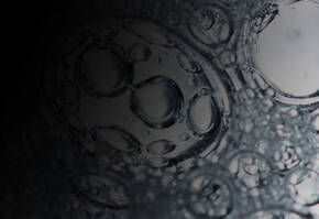 Close-up of clear bubbles on a dark surface, showcasing intricate patterns and reflections.