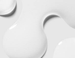 Gouttes de peinture blanche sur un fond gris, creant un effet de texture fluide et moderne.