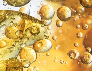 Lebendige Nahaufnahme von goldenen Blasen in einer Flussigkeit, die Licht reflektiert und eine faszinierende Textur zeigt.