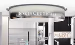 Ein moderner Empfangsbereich mit einem runden SkinCeuticals-Schild uber dem Empfangstresen.