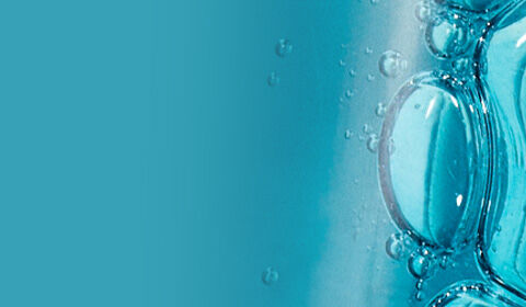 Close-up of blue bubbles in a transparent container, with a blurred white background.
