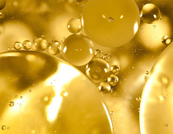 Gros plan sur des bulles dorees et des spheres de differentes tailles flottant dans un liquide lumineux.