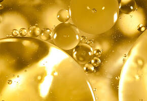 Gros plan sur des bulles dorees et des spheres de differentes tailles flottant dans un liquide lumineux.