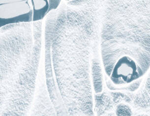 Eisige Oberflache mit zarten, gefrorenen Strukturen, die in sanften Blau- und Weißtonen schimmern.