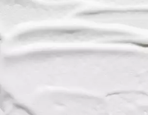 Creme blanche lisse etalee, texture onduleuse, evoquant la douceur et la legerete.