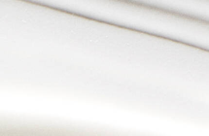 A close-up of a white surface featuring soft, wavy lines creating a subtle texture.