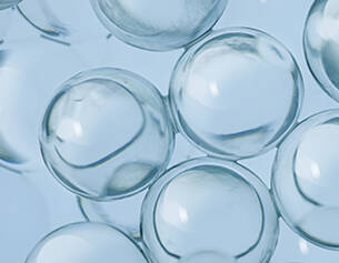 Des bulles transparentes prises de pres, flottant doucement sur un fond bleu clair.