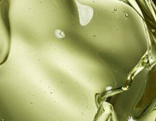 Gouttes d'huile d'olive verte se melangeant, creant une texture fluide et brillante.