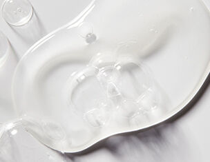 A clear, viscous gel pooled on a white surface, showcasing its smooth texture and reflective quality.