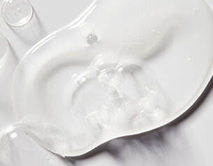 A clear, viscous gel pooled on a white surface, showcasing its smooth texture and reflective quality.