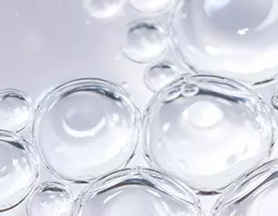 Transparente Wasserblasen vor hellem Hintergrund, die Licht reflektieren und eine beruhigende, klare Asthetik schaffen.