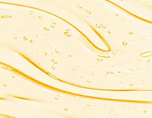 Close-up of smooth, flowing yellow liquid with small bubbles, creating a wave-like texture.