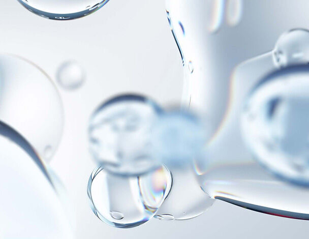 Transparente Wasserblasen auf leicht verschwommenem Hintergrund, die Licht reflektieren und einen frischen Eindruck vermitteln.