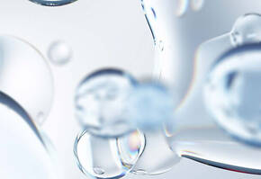 Transparente Wasserblasen auf leicht verschwommenem Hintergrund, die Licht reflektieren und einen frischen Eindruck vermitteln.