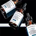 Drei Flaschen SkinCeuticals Vitamin C Serum vor einem dunkel schimmernden Hintergrund