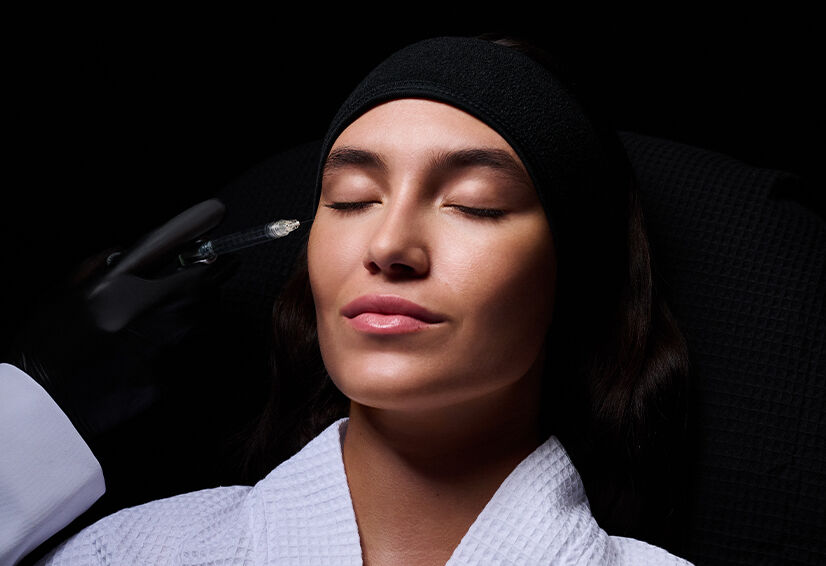 Un professionnel de la sante esthetique prepare une injection sur le visage d'un homme allonge.