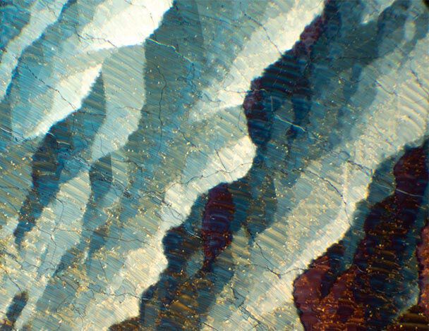 Details colores et textures d'une surface minerale, presentant des nuances de bleu, blanc et or.