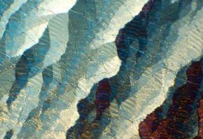 Details colores et textures d'une surface minerale, presentant des nuances de bleu, blanc et or.