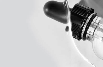 Close-up of a white medical device featuring a transparent component and a black dial, set against a light gray background.