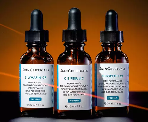 Trois flacons de serum de la marque SkinCeuticals, avec des pipettes, sur un fond sombre et lumineux.