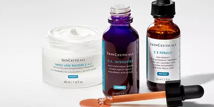 Trois flacons de serum et un pot de creme, disposes sur un fond blanc, presentant des produits de soin de la peau.