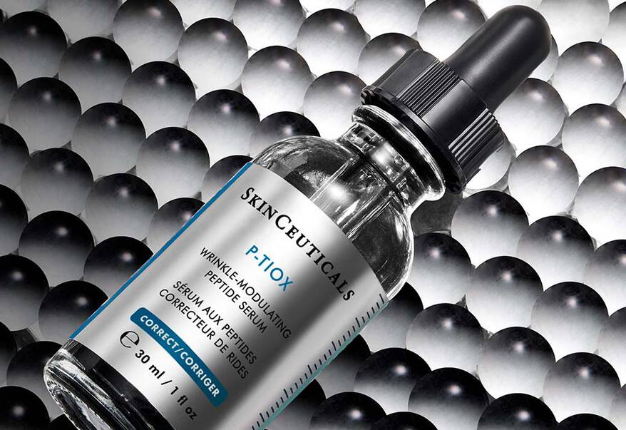 Quatre serums SkinCeuticals – C E Ferulic, H.A. Intensifier, A.G.E. Interrupter Ultra Serum et Phyto Corrective – sur un fond sombre, entoures d’un halo de lumiere.