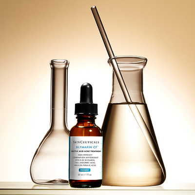 Flacons en verre et une pipette de serum SkinCeuticals Silymarin CF sur fond beige.