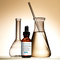 Flacons en verre et une pipette de serum SkinCeuticals Silymarin CF sur fond beige.
