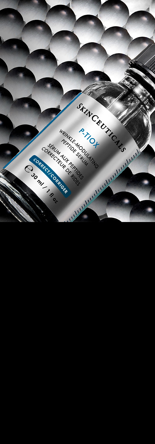 Eine Flasche SkinCeuticals Discoloration Defense Serum liegt schräg auf einem Hintergrund aus dicht gepackten, glänzenden schwarzen und grauen Kugeln, was eine texturierte und wissenschaftliche Ästhetik erzeugt.